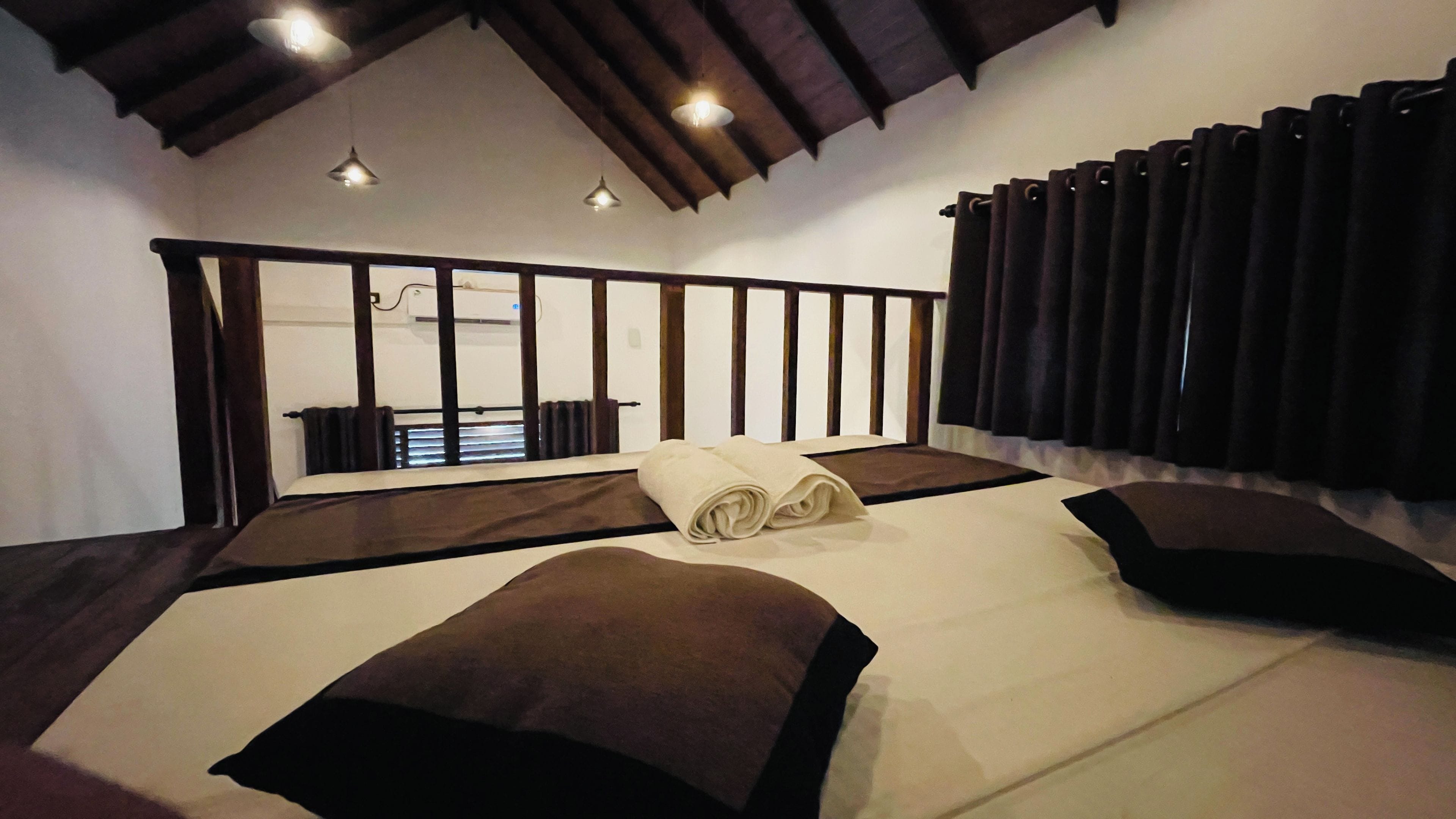 Een slaapkamer met een groot bed, uitzicht op een balkon en een plafond met zichtbare balken.