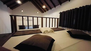 Ein Schlafzimmer mit einem großen Bett, einem Blick auf einen Balkon und einer Decke mit sichtbaren Holzbalken.