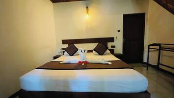 A hotel room with a bed, a nightstand, a bedside table, and a door.