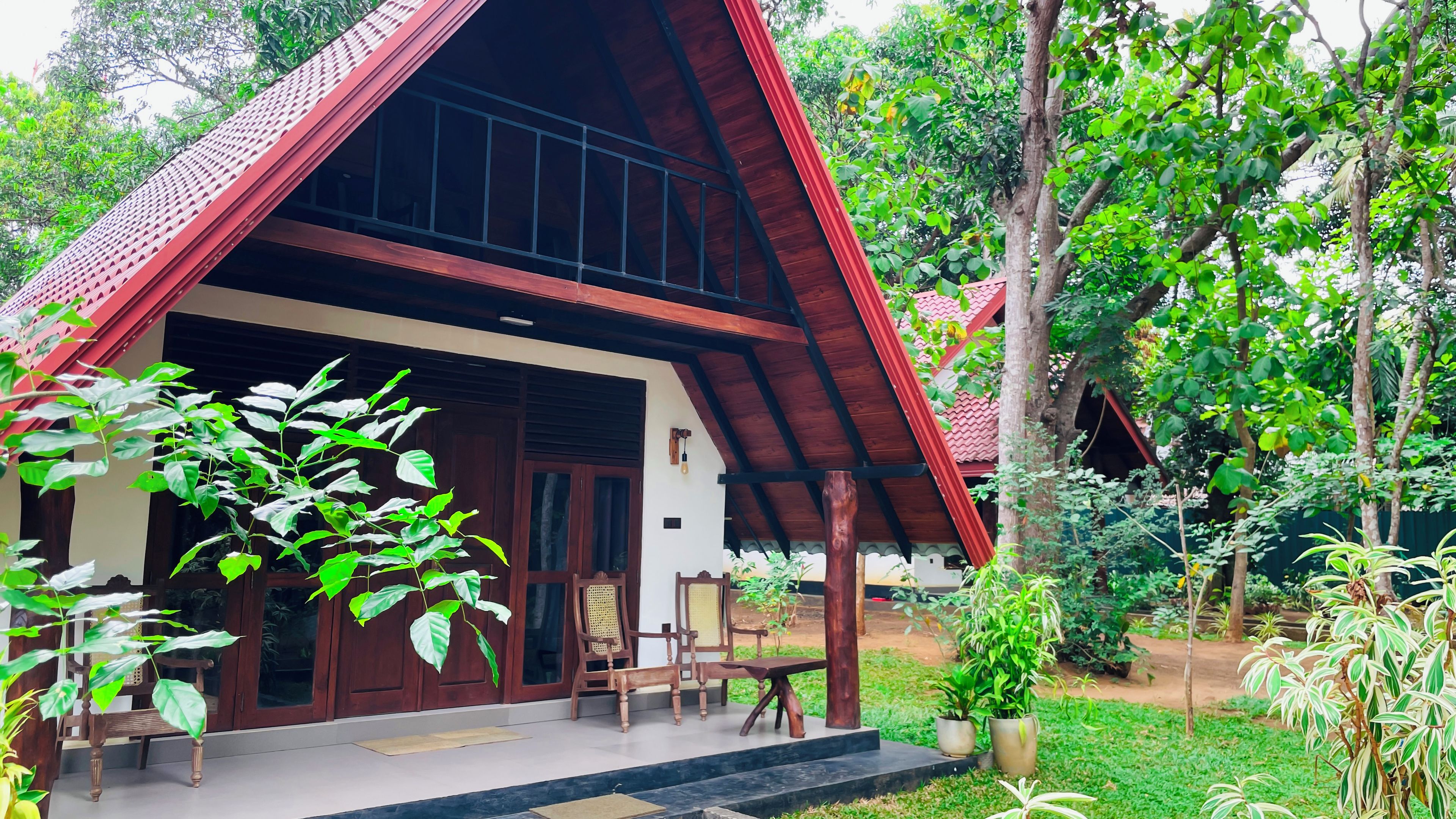 A traditional house with a sloped roof, wooden exterior, and a porch with chairs and a table.
