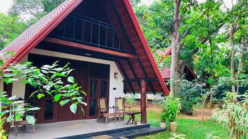 A traditional house with a sloped roof, wooden exterior, and a porch with chairs and a table.