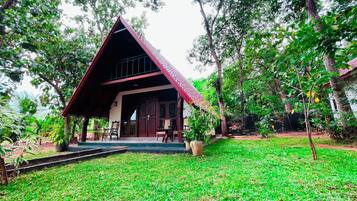 A house with a sloped roof, a porch with chairs, and a well-maintained lawn.