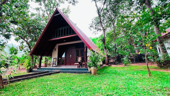 A house with a sloped roof, a porch with chairs, and a well-maintained lawn.