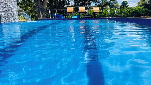 Ein klares Schwimmbecken mit einer Steinmauer an einer Seite und einem Metallgeländer.