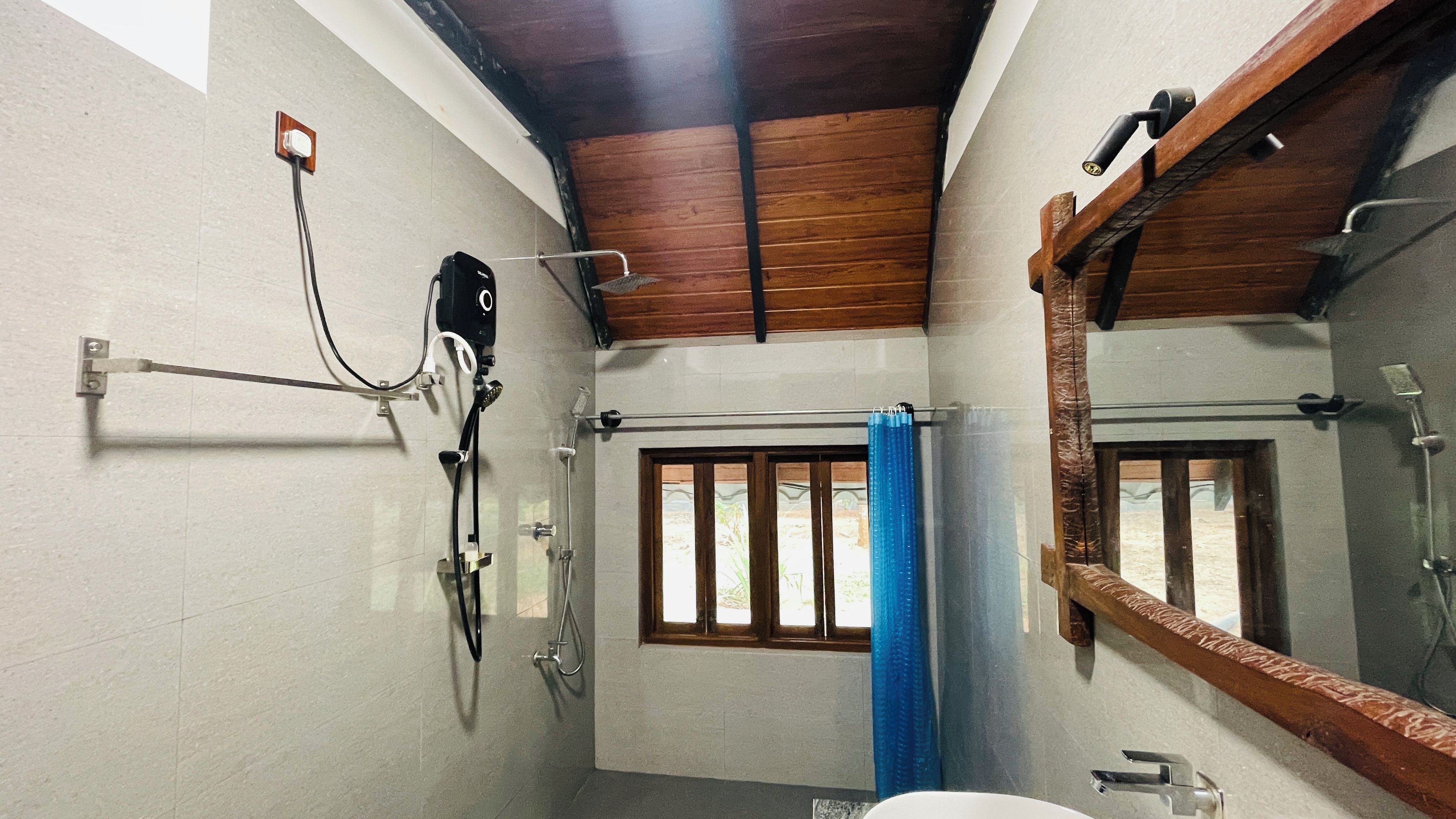 A bathroom with a shower, a mirror, and a window.