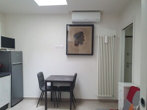 Uma cozinha compacta com mesa e cadeiras, geladeira embutida, aparelho de ar condicionado e radiador.