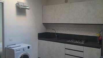 A compact kitchen with a built-in washer, a sink, and a gas stove.