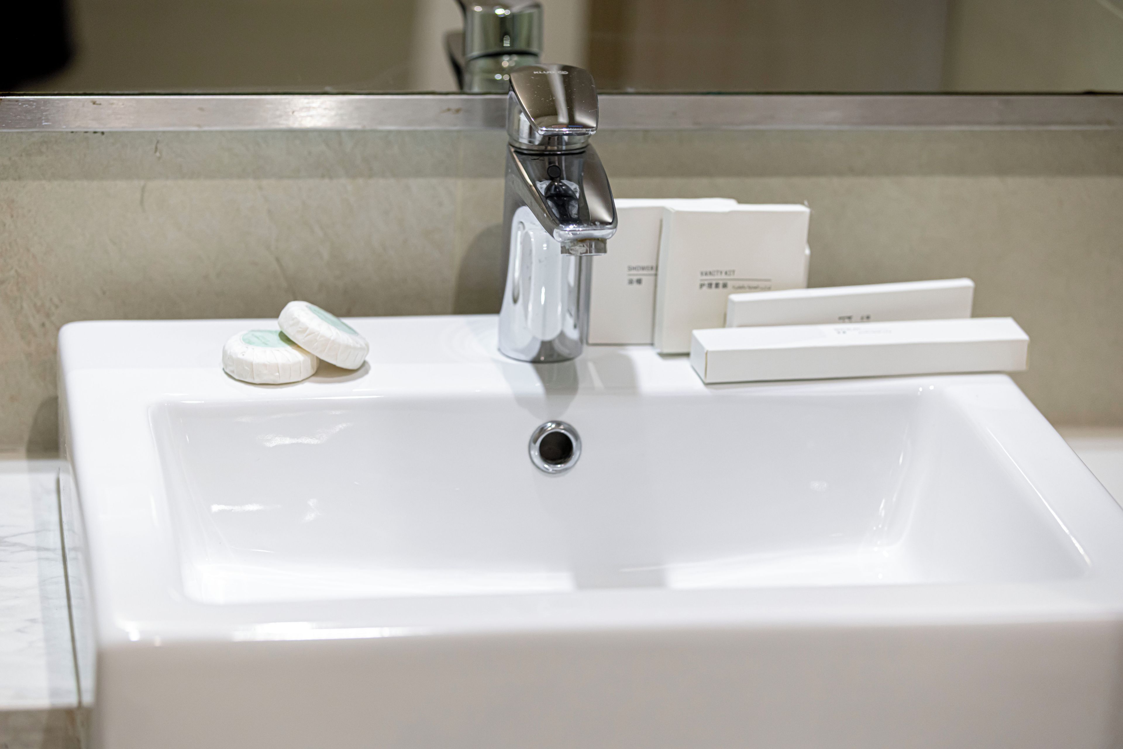 Un lavabo da bagno con un rubinetto cromato e uno specchio sopra.
