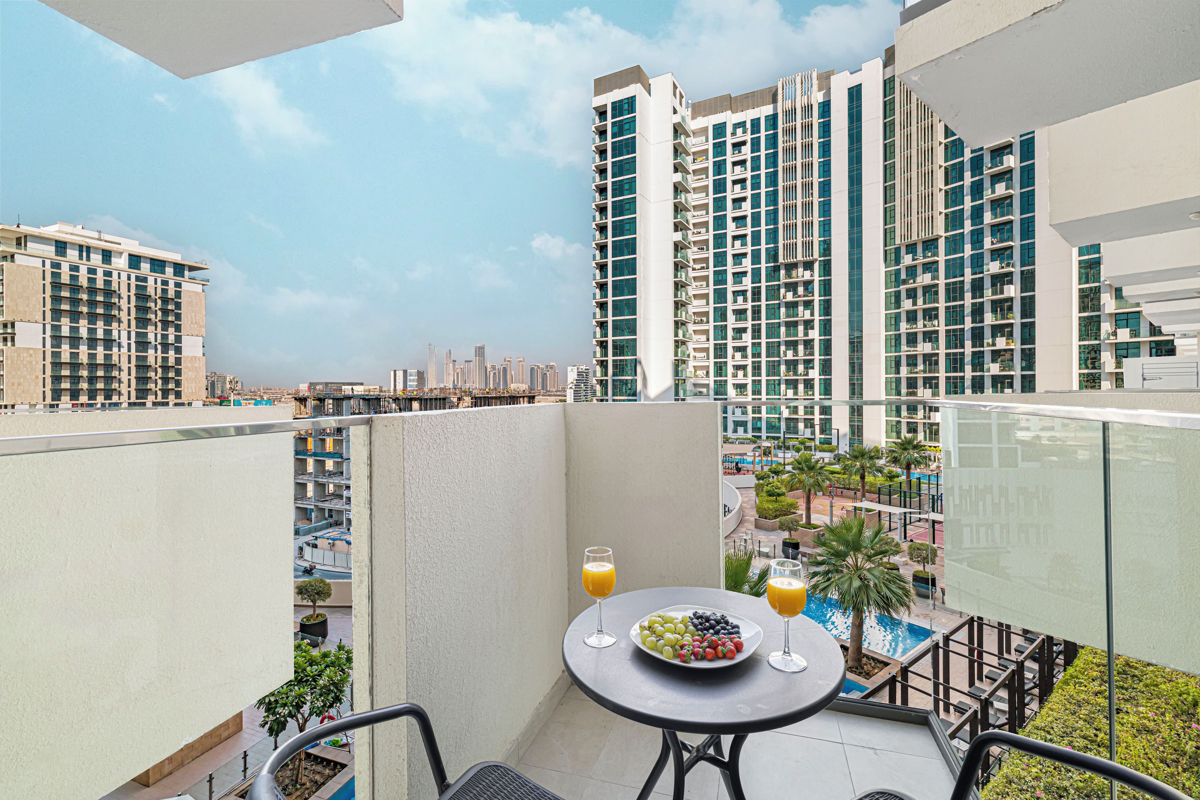 A balcony with a table, chairs, a plate of fruit, and a glass of orange juice.