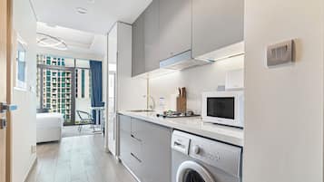 Cozinha moderna com máquina de lavar embutida, micro-ondas e área de jantar com vista para a cidade.