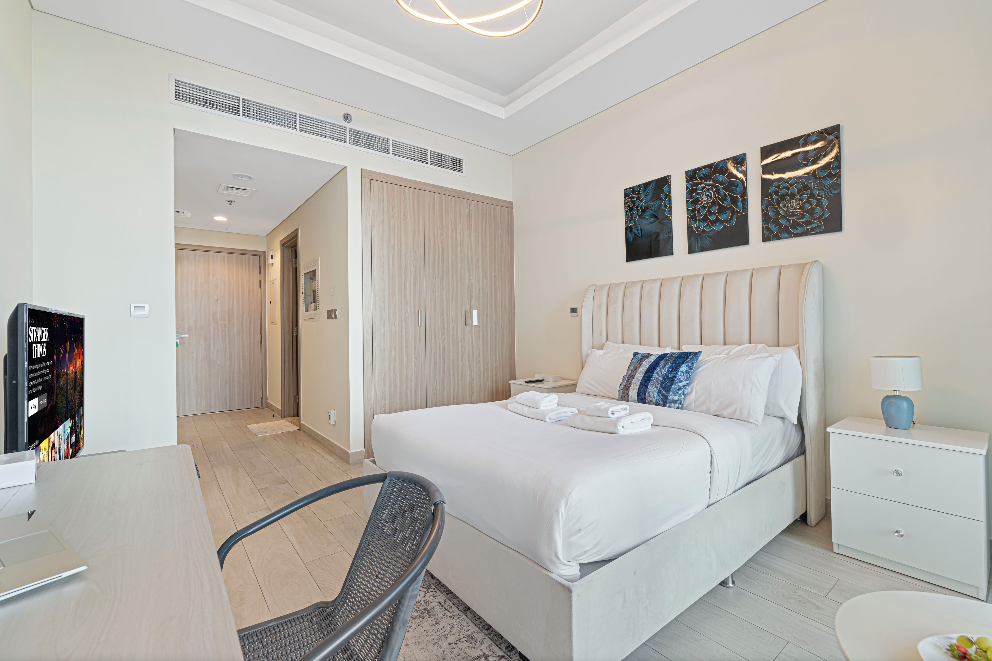 A hotel room with a bed, bedside table, lamp, chair, and a television.
