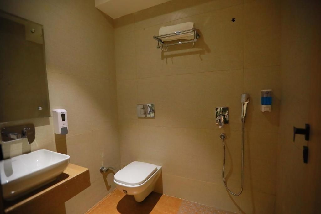 Un bany amb vàter, rentapel, mirall, prestatge per a tovalloles i dutxa.