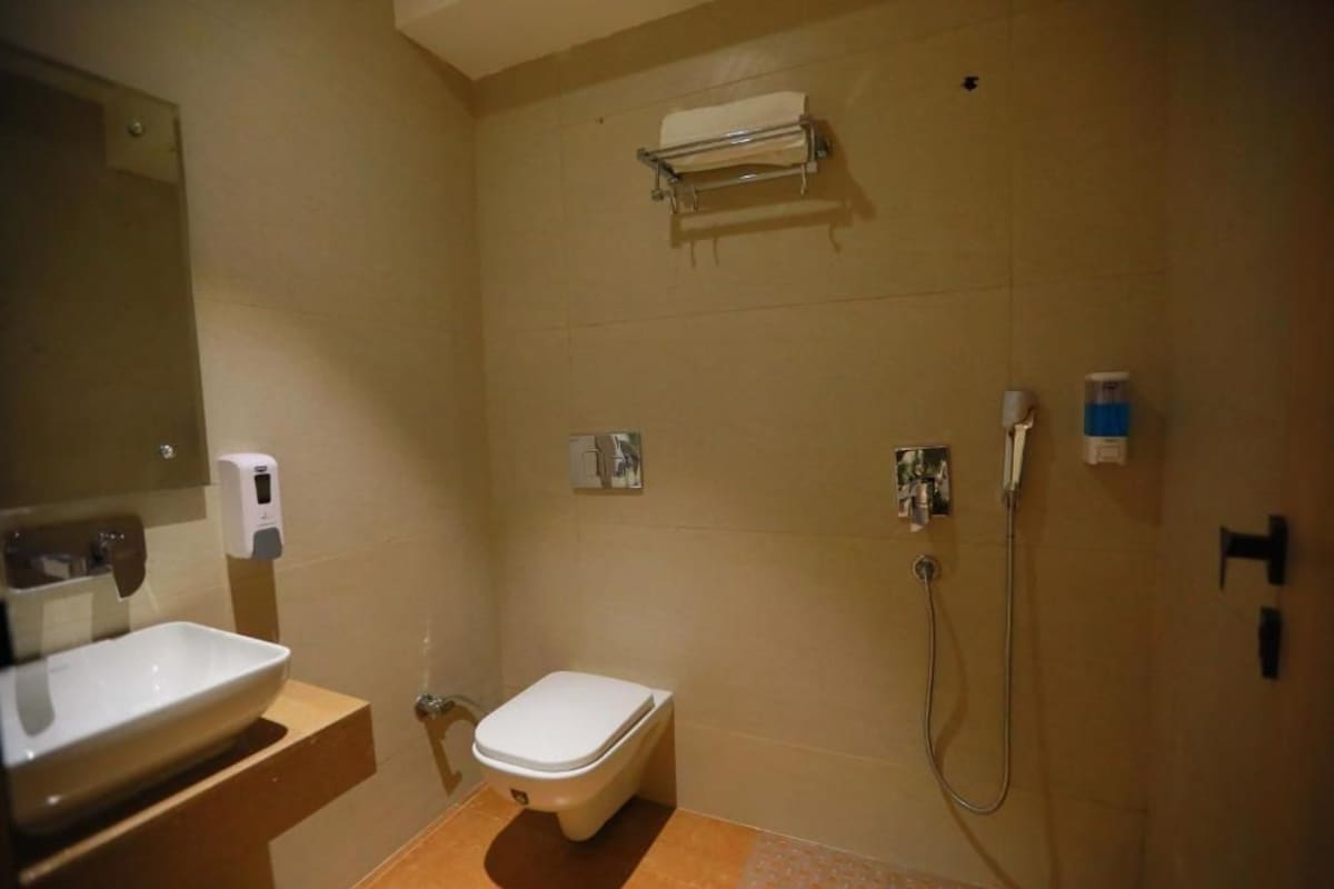 Ein Badezimmer mit Toilette, Waschbecken, Spiegel, Handtuchhalter und Dusche.