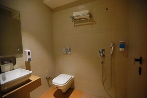 Un baño con inodoro, lavamanos, espejo, toallero y ducha.