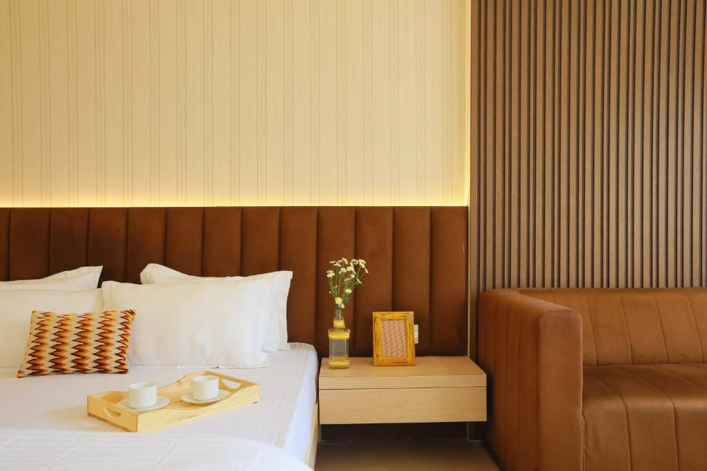 Una habitación de hotel con cama, mesita de noche y un sofá de cuero marrón.
