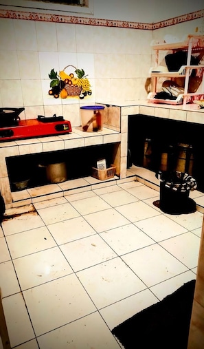 A kitchen with a tiled backsplash, a red induction cooktop, a sink, and a black trash bin.