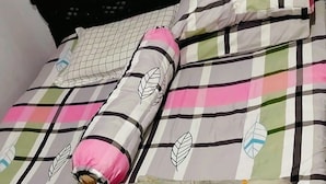 A bed with a black headboard, multiple pillows, and a patterned bedspread. - HST Coffee and Homestay Wonosobo (Wonosobo)