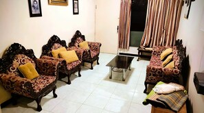 Una sala de estar con cuatro sofás estampados, una mesa de centro y un televisor.