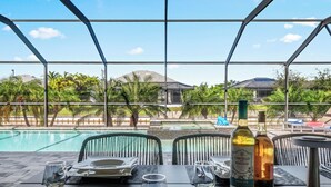 Área de refeições com vista para uma piscina, assentos externos e uma mesa posta para dois.