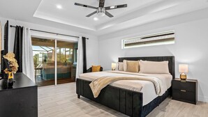 Quarto moderno com cama grande, luminárias de cabeceira e ventilador de teto.