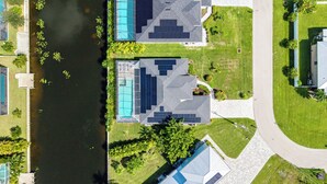 Vista aérea de uma área residencial com duas casas, uma piscina e um rio.