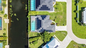 Vue aérienne d’un quartier résidentiel avec deux maisons, une piscine et une rivière.