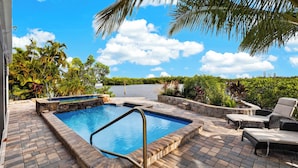 A swimming pool with a stone border, surrounded by a patio area with outdoor furniture. - Kayak + Fishing Dock | Pool + Spa | Mangroves + Beaches | Sanctuary Point (Bonita Springs)