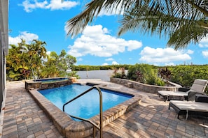 Una piscina con borde de piedra, rodeada por una zona de patio con mobiliario exterior.