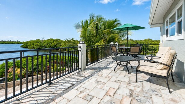 A patio with outdoor furniture, a table, and an umbrella. - Kayak + Fishing Dock | Pool + Spa | Mangroves + Beaches | Sanctuary Point (Bonita Springs)