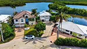 A residential area with houses, a car, and a body of water. - Kayak + Fishing Dock | Pool + Spa | Mangroves + Beaches | Sanctuary Point (Bonita Springs)