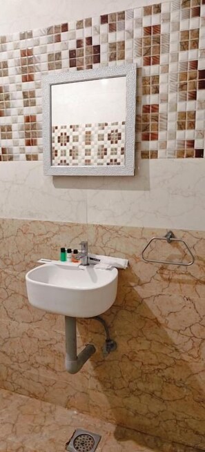 Une salle de bain avec un lavabo, un miroir et un mur recouvert de carreaux.