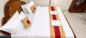 A neatly made bed with white linens and a red and gold striped blanket.