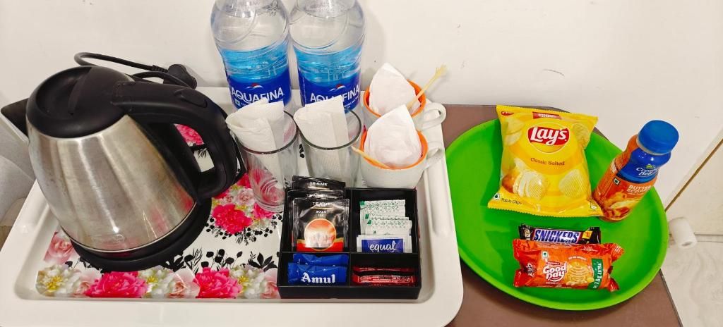 A tray with a kettle, bottled water, snacks, and a green plate.