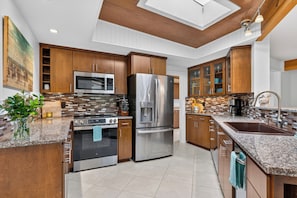 A modern kitchen with stainless steel appliances, wooden cabinets, and a tiled backsplash. - Ocean-View Deck + Fire Pit + BBQ | Short Walk to the Beach | The Grey Piper (Arch Cape)