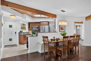 Een moderne keuken met houten kastjes, een centraal eiland en een eethoek met een houten tafel en stoelen.