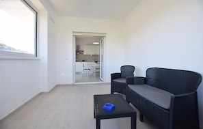 Un balcon avec un canapé en osier, une petite table et une vue sur un coin cuisine.