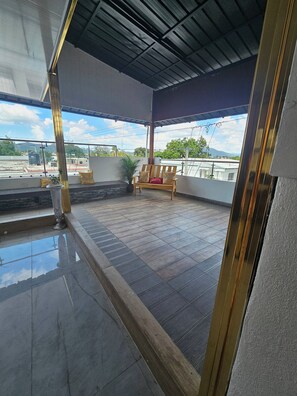 A covered balcony with a bench and potted plants. - - Bonao Yaneris Luxury Apartament (Bonao)