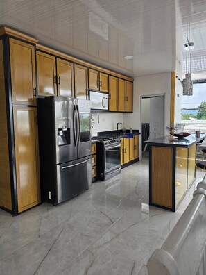 A modern kitchen with stainless steel appliances, wooden cabinetry, and a central island. - - Bonao Yaneris Luxury Apartament (Bonao)