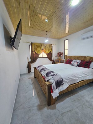 A bedroom with a bed, a television mounted on the wall, a window with curtains, and a ceiling fan. - - Bonao Yaneris Luxury Apartament (Bonao)