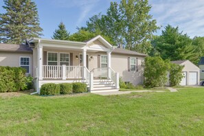 Ein eingeschossiges Haus mit Veranda, Garage und gepflegtem Rasen.