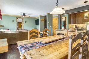 Ein Essbereich mit Holztisch und -stühlen, einem Deckenventilator und einer Küche mit Holzausbau und einer Mikrowelle.