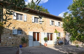 A two-story stone building with multiple windows, doors, and a small garden area with potted plants. - Gorgeous home in Sansepolcro with WiFi (Sansepolcro)
