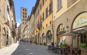 A pedestrian street lined with historic buildings, outdoor seating at a café, and a clear blue sky. - Gorgeous home in Sansepolcro with WiFi (Sansepolcro)