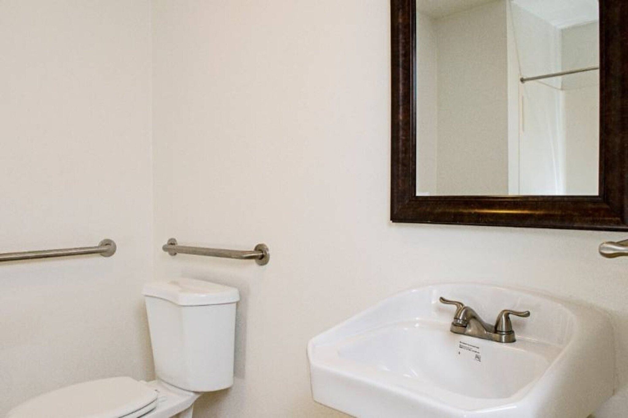 A bathroom with a toilet, a sink, and a mirror.