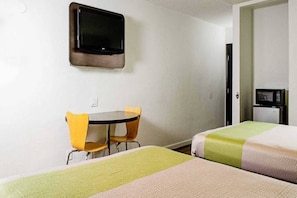 Une chambre d’hôtel équipée d’un lit, d’un bureau, d’une chaise, d’une télévision et d’un four à micro-ondes.
