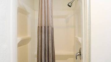 A bathroom with a shower curtain, a showerhead, and a door handle.