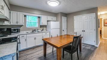Una cocina con armarios blancos, una mesa de comedor de madera y un horno empotrado.
