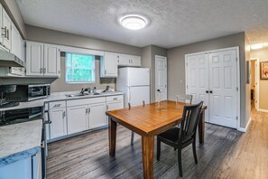 A kitchen with white cabinets, a wooden dining table, and a built-in oven.