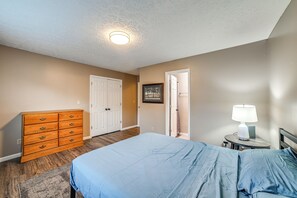 A bedroom with a bed, dresser, and a door leading to another room.