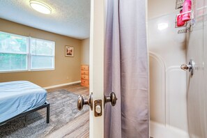 A bedroom with a bed, a dresser, and a shower.